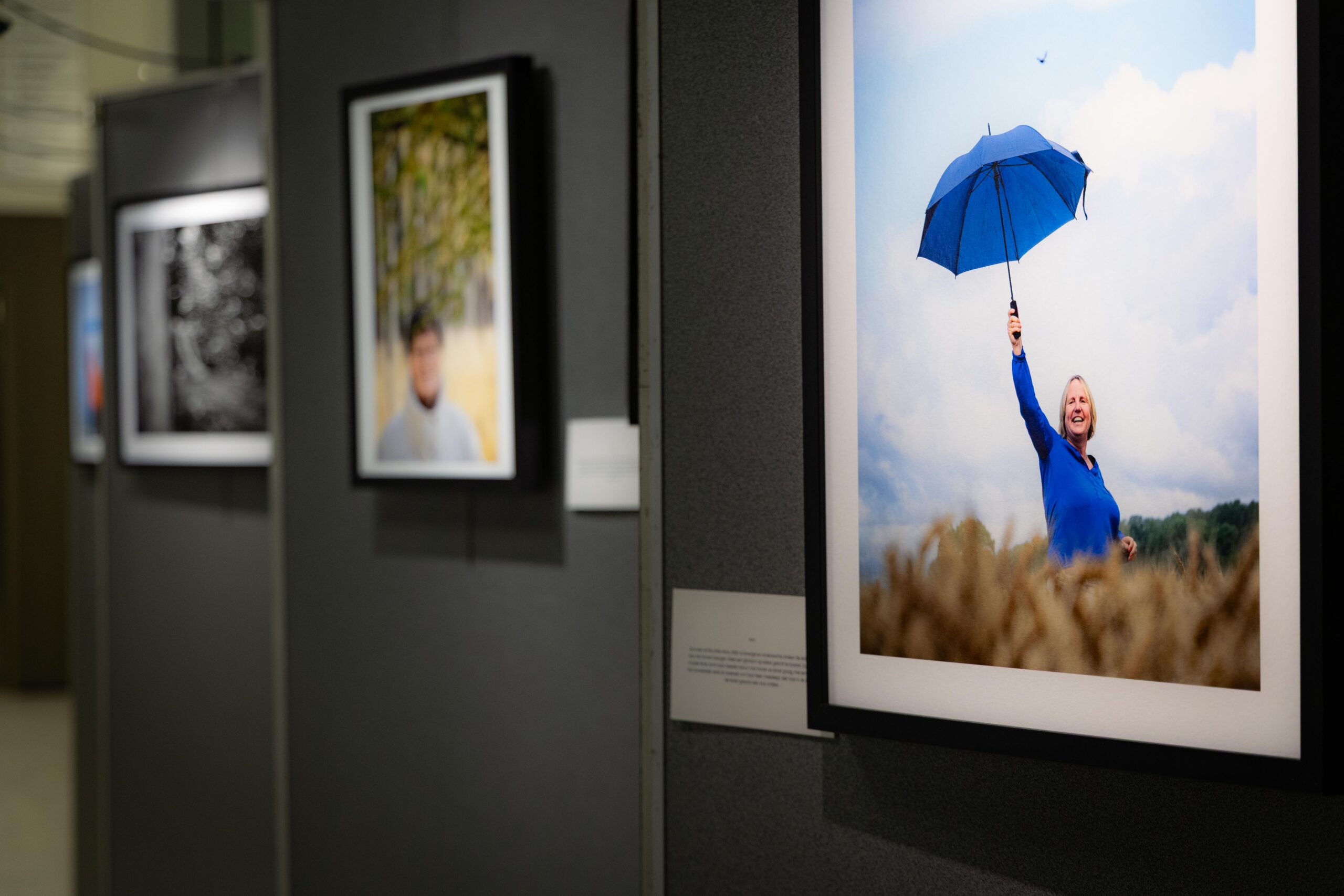 Foto van op de fotovernissage 'Houvast'. We zien drie foto's van personen met jongdementie, gefotografeerd door Ann De Wulf.
