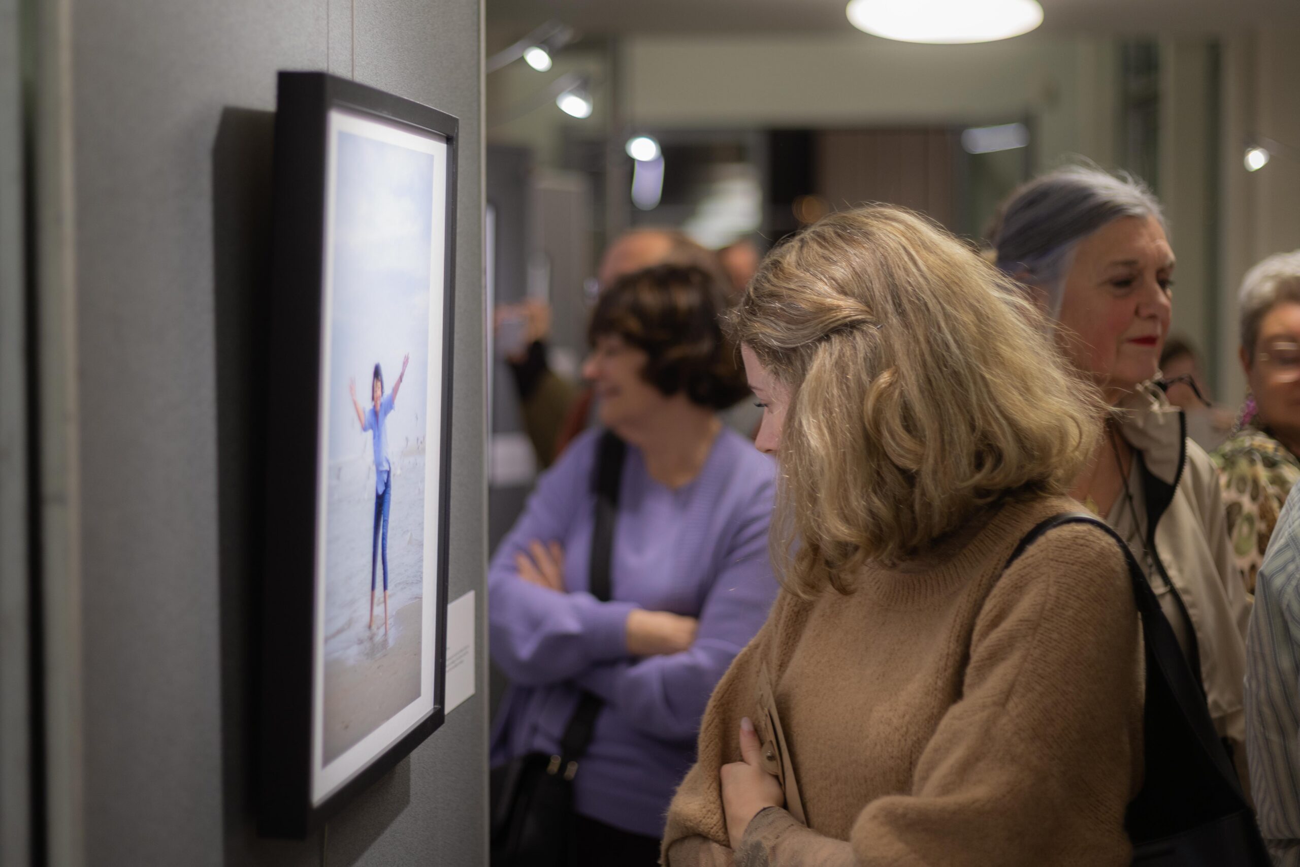 Foto van op de fotovernissage 'Houvast'. Een bezoeker kijkt naar een van de portretten.
