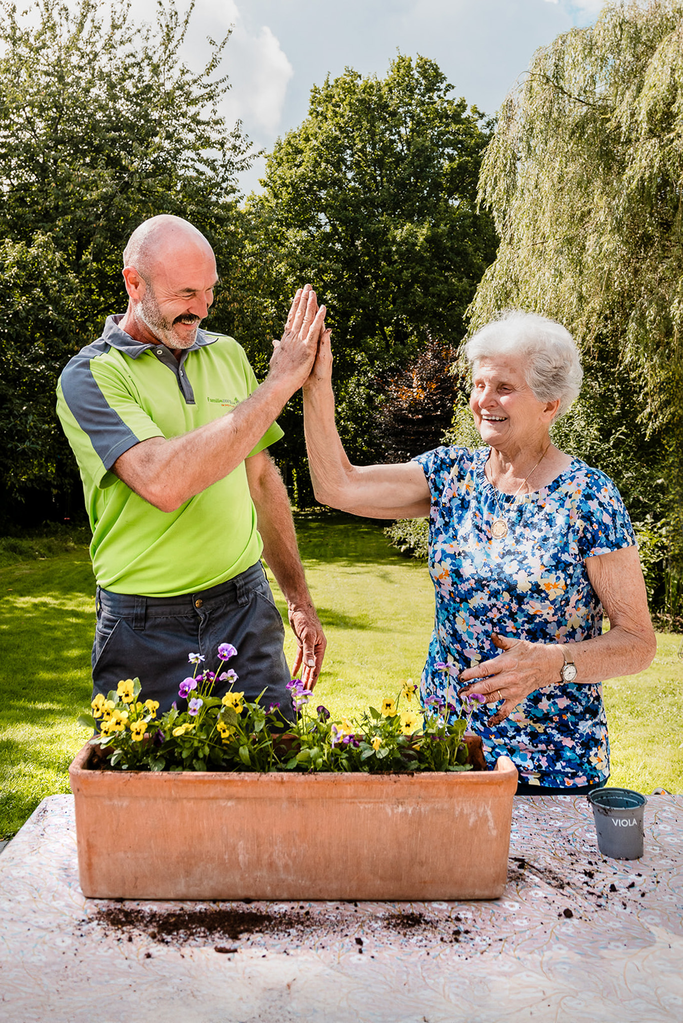 Een klusjesman van Familiezorg geeft high five aan cliënte.