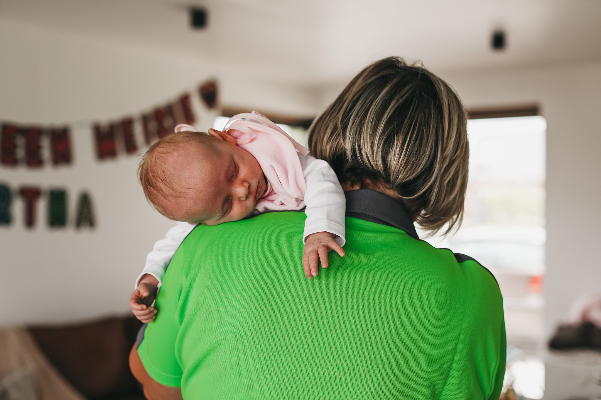 Kraamzorg verzorgende van Familiezorg met een baby over haar schouder. De baby slaapt.