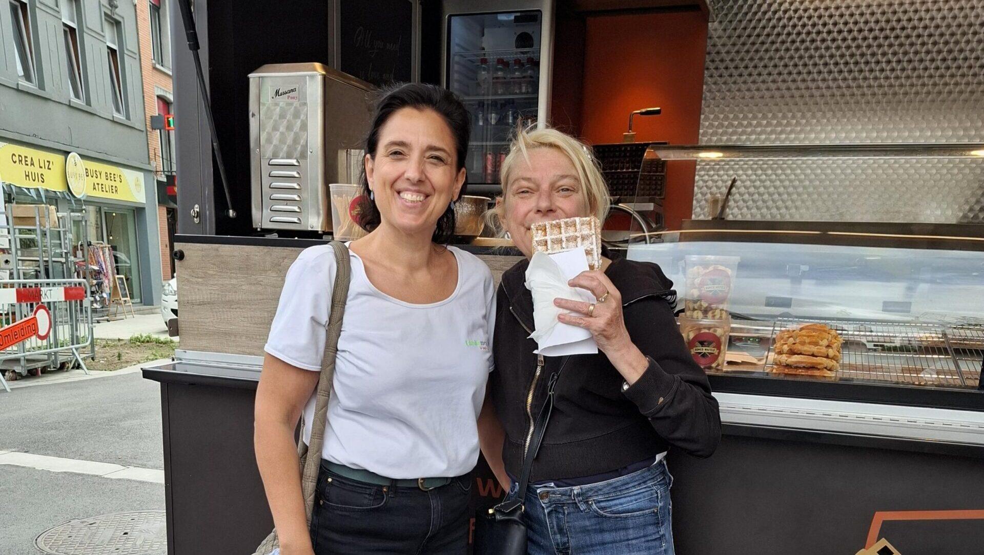 Verzorgende Carolien en cliënte Cindy bij een wafelkraam.
